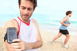 Male Using a Device While Running on Beach